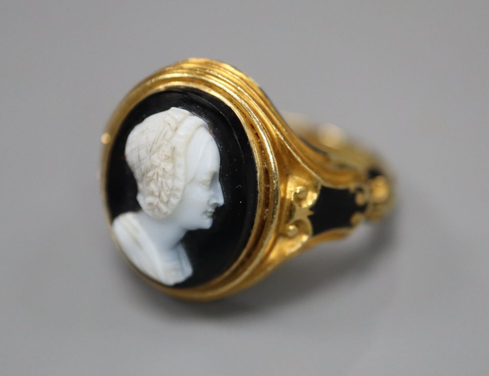 A Victorian 18ct gold cameo ring, of carved scrolled design with black enamelled decoration and hairwork panel, size M/N,